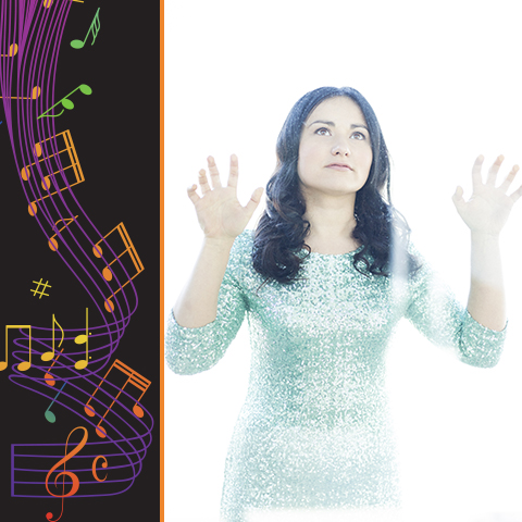 Dinara Klinton, a woman with long black hair and in a blue glitter dress, is holding her hands up with palms facing the camera, pressed against a clear glass wall, and looking up to the sky. 